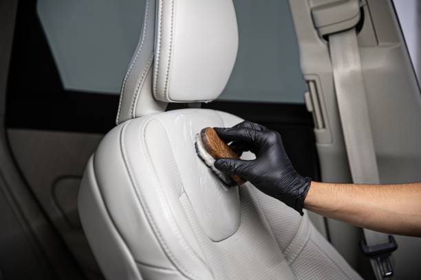 Man car detailing studio worker cleaning car leather seat with a brush. Car detailing